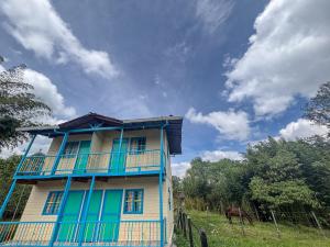 een blauw-wit huis met een paard in een veld bij Las Casas de Tomate in Guatapé