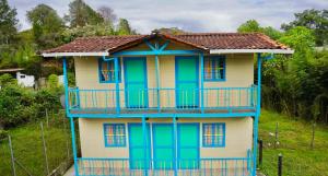 een blauw en geel huis met een balkon bij Las Casas de Tomate in Guatapé