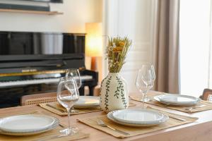 Una mesa con platos y vasos y un jarrón con flores. en Le Pianiste, en hypercentre avec balcon, en Limoges 20 fotos más