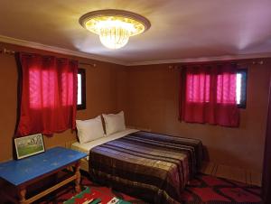 瓦尔扎扎特Bivouac Lot Of Stars的一间卧室配有一张床、红色窗帘和吊灯