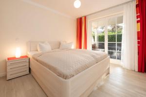 a white bedroom with a large bed and a window at Villa Mara Wohnung 3 in Baabe