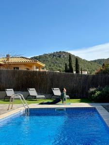 Eine Person sitzt auf einem Surfbrett neben einem Schwimmbecken in der Unterkunft Modernes Einfamilienhaus mit privatem Pool Villa Medes Mar in l'Estartit - b52677 in Torroella de Montgrí