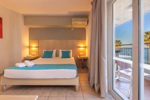 a bedroom with a bed and a large window at Kos City Sunstone Hotel in Kos