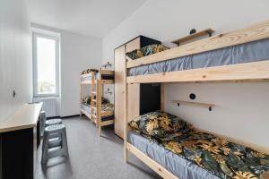 a dorm room with bunk beds and a desk at Najtańsze noclegi Piłsudskiego 93 in Łódź