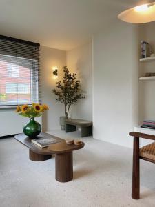 a living room with a table and a vase with flowers on it at House W - North Sea Stays in De Haan