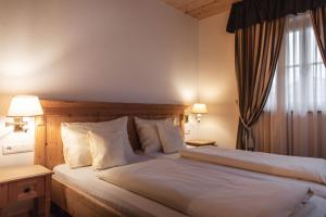 a bedroom with a bed with white sheets and a window at Ortnerhof in Gais