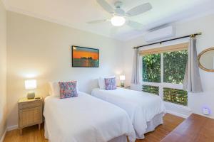 two beds in a room with a window at Hale Cassia in Princeville