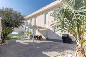 Un patio con una mesa y sillas frente a un edificio. en Villa Oasis del Sol Gran Alacant by United Renters, en Puerto Marino
