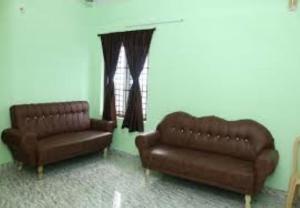 a living room with two leather couches and a window at Villa Saravana in Puducherry
