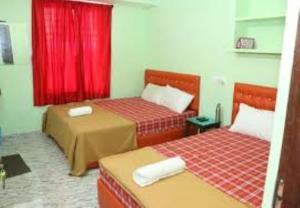 a room with two beds and a red curtain at Villa Saravana in Puducherry