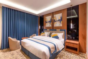 a bedroom with a large bed and blue curtains at Medad Al Salam Apartments in Dammam