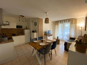 eine Küche und ein Wohnzimmer mit Tisch und Stühlen in der Unterkunft Escapade Uzétienne Cœur de ville et Parking in Uzès
