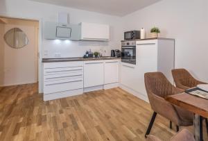 a kitchen with white cabinets and a wooden floor at Hochkopf Suite - Premium Apartment - Schwarzwald in Bühl