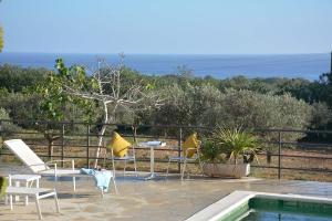 eine Terrasse mit Stühlen, einem Tisch und einem Pool in der Unterkunft Charming Traditional Sea View Home in Es Cana