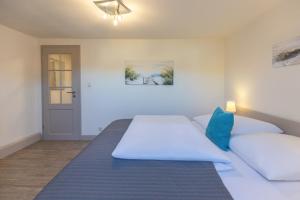 a bedroom with a bed with white sheets and blue pillows at Matthis Skipperhuus in Husum