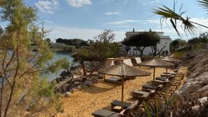 a row of umbrellas and chairs on a beach at Sirena Bay Beach House and Luxury Suites in Protaras