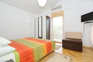 una camera da letto con un letto colorato e una sedia di Ferienapartment Mit Balkon Für Fünf Personen a Gornji Karin (Carino)