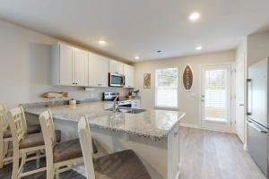 a kitchen with white cabinets and a counter with chairs at Coastal Pines "2" in Ocean Isle Beach