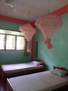 two beds in a bedroom with pink drapes at Wellassa holly day in in Monaragala +2 photos