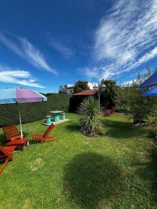a yard with chairs and an umbrella and a table at Complejo LA MERLINA in Merlo