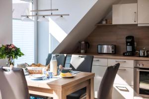 a kitchen with a wooden table and chairs at Moderne Maisonettewohnung In Meernähe in Börgerende-Rethwisch