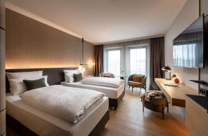 a hotel room with two beds and a desk at ATLANTIC Hotel Heidelberg in Heidelberg