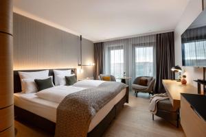 a hotel room with a large bed and a chair at ATLANTIC Hotel Heidelberg in Heidelberg