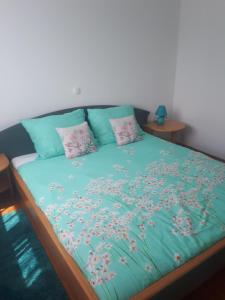 a bed with blue sheets and pink pillows on it at Ferienwohnung Mit Herrlicher Aussicht in Dobreć
