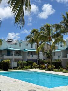 a pool with palm trees in front of a building at Bleu Des Zil in Grand-Baie +4 photos