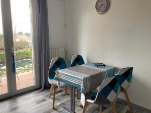 a dining room with a table and chairs and a clock at Courthézon Entre vignes et Village, T2 indépendant in Courthézon