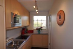 a kitchen with a sink and a refrigerator at Ferienwohnung Biberhüs Obergeschoss In Archsum in Archsum +12 photos