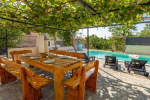 a wooden table and chairs and a swimming pool at Schönes Ferienhaus In Modrusani Mit Großem Garten in Žminj
