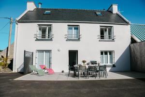 a white house with a table and chairs at Maison de campagne avec grand jardin pour 8 in Plouguerneau