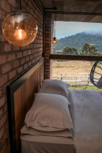 Bett in einem Backsteinzimmer mit Fenster in der Unterkunft Monte Sião Château in Urubici