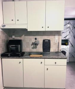 a kitchen with white cabinets and a black counter top at Relatives Apartment in Mytilene