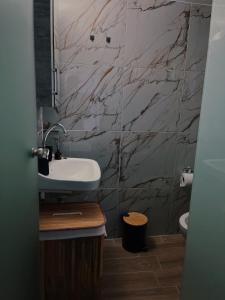 a bathroom with a sink and a marble wall at Relatives Apartment in Mytilene +16 photos
