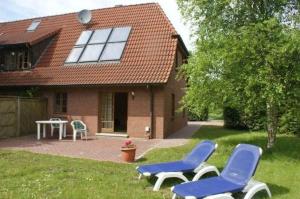 Dos sillas azules y una mesa frente a una casa. en Ferienwohnung Schoenk In Havetoft, en Havetoft