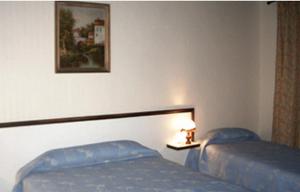 a bedroom with two beds and a picture on the wall at Avenir Hotel in Paris