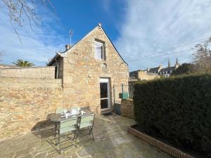 a stone house with a table and chairs on a patio at Maison bretonne 2 personnes centre ville St Pol de Léon in Saint-Pol-de-Léon