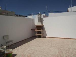 a white wall with a table and a chair on a patio at Casa Correia in Monte Gordo