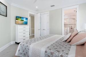 a white bedroom with a large bed and a television at AMI Beach Oasis in Bradenton Beach