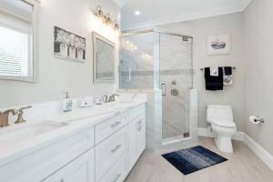 a white bathroom with a shower and a toilet at AMI Beach Oasis in Bradenton Beach +12 photos
