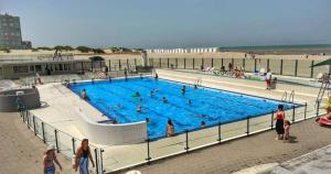 Menschen in einem Schwimmbad am Strand in der Unterkunft Premium Holidays - Studio Vriedom at the sea in Oostduinkerke