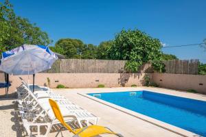 a swimming pool with chairs and an umbrella next to it at Ferienhaus Leone in Bibići