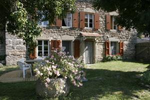 a stone house with a table and flowers in the yard at La maison d'Anastasie in Saint-Étienne-du-Vigan