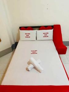a red and white bed with two pillows and a paper on it at WJV Inn San Carlos in San Carlos
