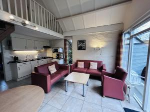 ein Wohnzimmer mit Sofas und einem Tisch sowie eine Küche in der Unterkunft Bungalowpark Simpelveld - Delta 154 in Simpelveld