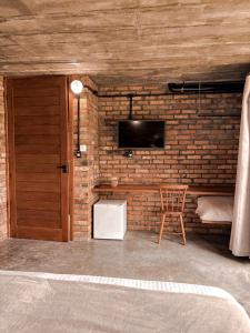 Zimmer mit Ziegelwand, TV und Stuhl in der Unterkunft Monte Sião Château in Urubici