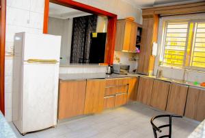 a kitchen with a white refrigerator and wooden cabinets at Stella Residence and Cuisine Kigali in Kigali
