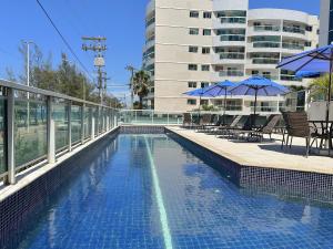 basen z leżakami i parasolami oraz budynek w obiekcie Loft de alto padrão e vista para o mar | MASD309 w mieście Macaé